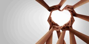 A group of students hands and arms clasp together in support to make the outline of a heart