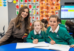 A photo showing a teacher and scholarship recipient with two female students