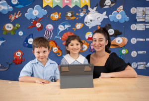 Photo of two students with a teacher in a classroom